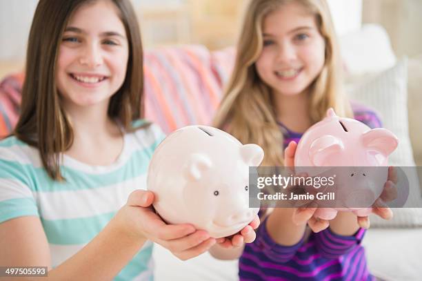friends holding piggy banks together - blonde girl piggy bank stock-fotos und bilder