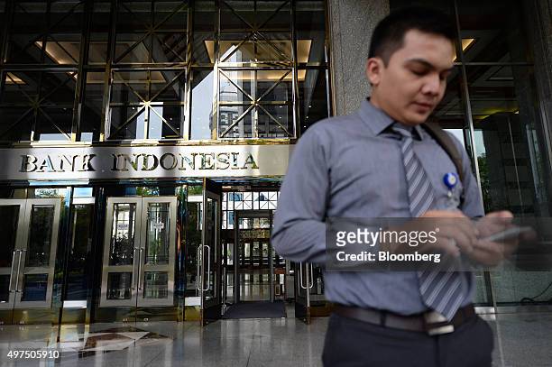 Pedestrian uses a smartphone outside the head office of Bank Indonesia in Jakarta, Indonesia, on Tuesday, Nov. 17, 2015. Indonesia's central bank cut...