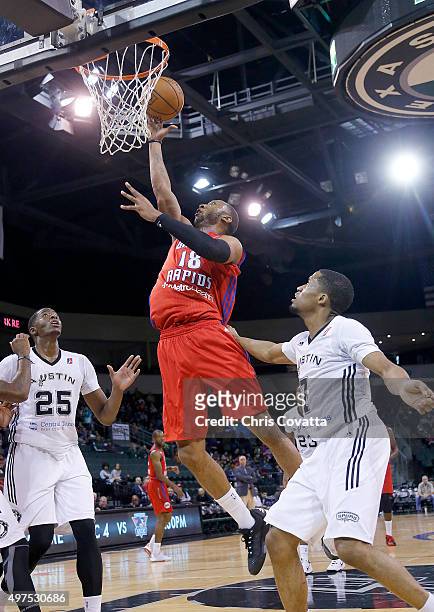 Kammeon Holsey of the Grand Rapids Drive shoots a layup between Cady Lalanne and Bryce Cotton of the Austin Spurs at the Cedar Park Center on...