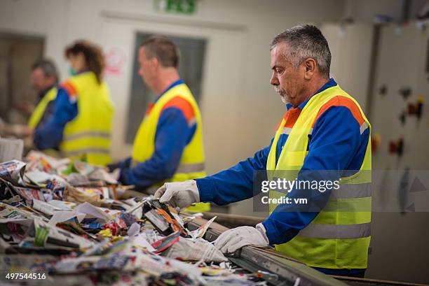 gruppe von arbeitnehmern sortierung zeitung beim recycling-plant - wiederverwertungsanlage stock-fotos und bilder