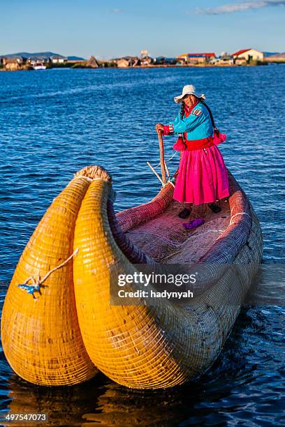 peruvian woman sailing between uros floating islands, lake tititcaca - uros stock pictures, royalty-free photos & images