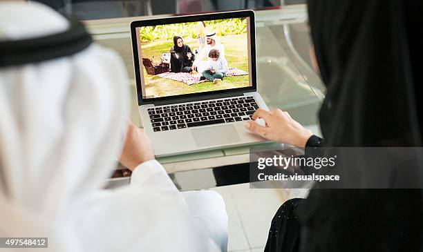 arabische paar anzeigen familie fotos zu hause auf laptop - emirati guy using laptop stock-fotos und bilder