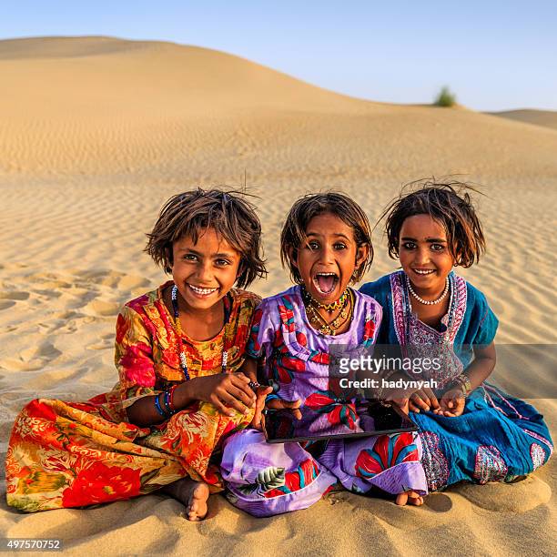 happy indian little girls using digital tablet, desert village, india - local gypsy stock pictures, royalty-free photos & images