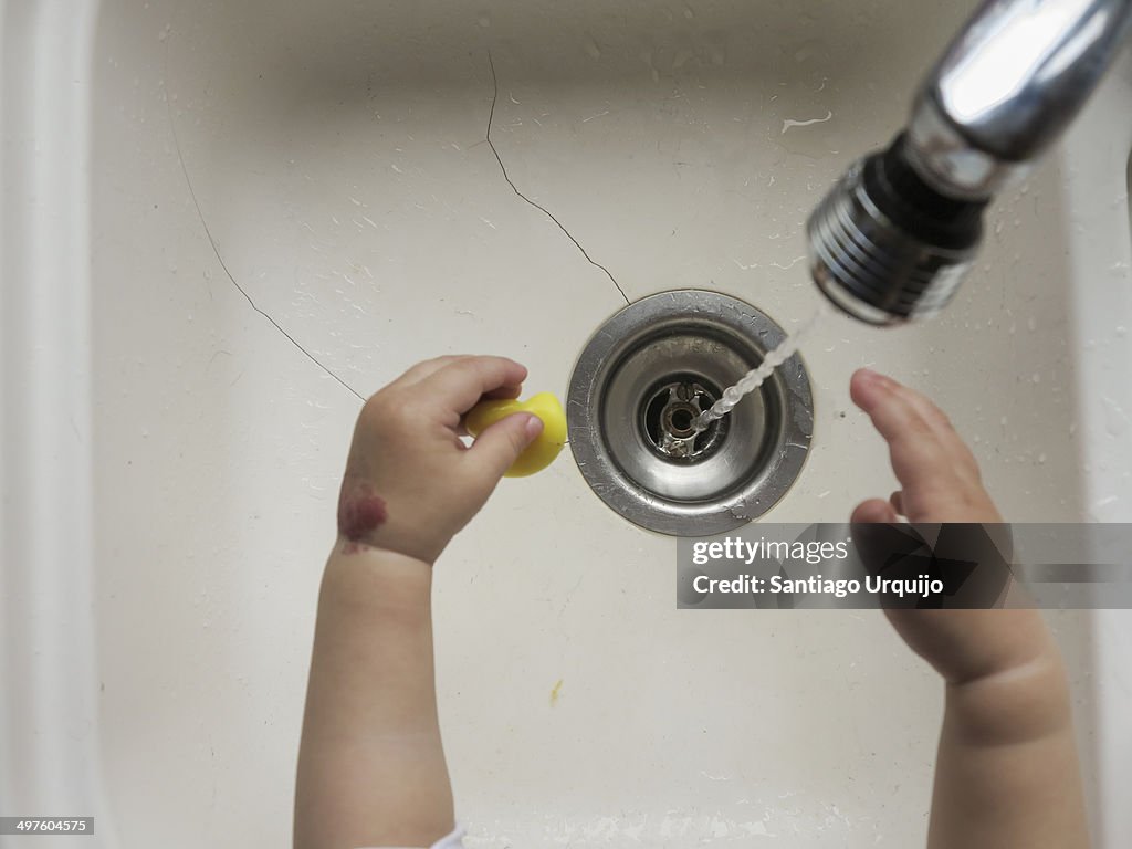 Child washing his hands in a kitchen sink