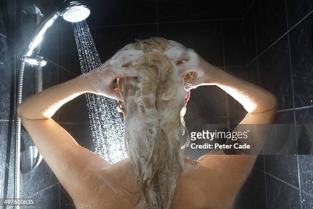 back of woman's head in shower washing hair - shampoo stock-fotos und bilder
