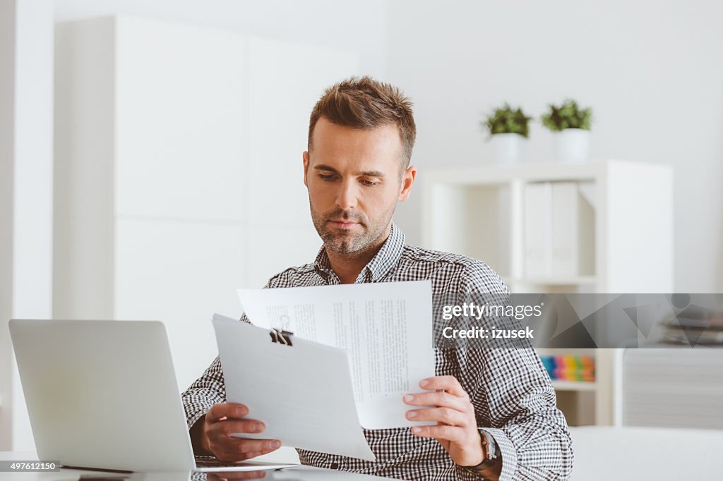 Man working in an home office, reading documents