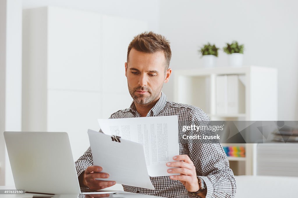 Homem a trabalhar em um escritório em casa, ler documentos