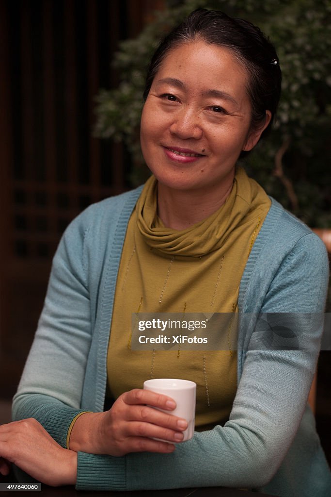 Souriant mature femme de l'Est asiatique tenant la tasse de thé