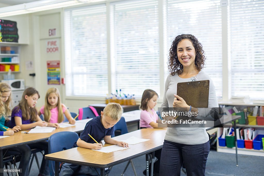Ethnic female elementary teacher posing in front of classroom