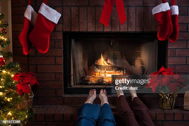 cozy christmas fireplace with grandmother and granddaughter warming feet - stocking feet stockfoto's en -beelden