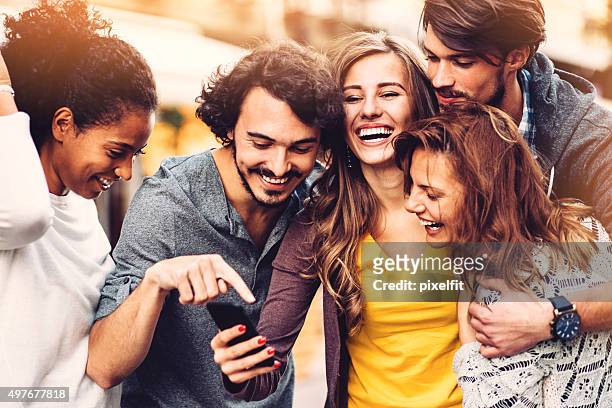 friends with phone outdoors - youth culture stock pictures, royalty-free photos & images