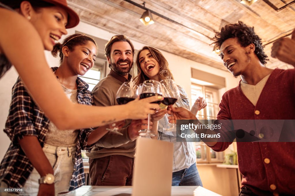 Group of cheerful colleagues toasting with wine in the office.