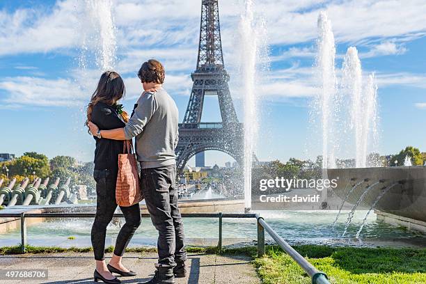 romantic young couple by the eiffel tower, paris, france - couple paris tour eiffel trocadero stockfoto's en -beelden