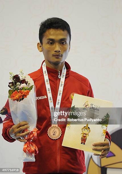 Gunawan of Indonesia celebrates with his bronze medal on the podium during the Men's 52kg Sanda Competition medals ceremony of the 2015 World Wushu...