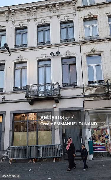 Two people walk past the Abdeslam family's apartment in Brussels' Molenbeek district, close to the Town's Square where a vigil was earlier held, on...