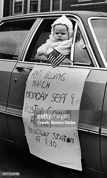 Person holds a baby up to the window of a car, during an anti-busing motorcade on Broadway in South Boston on Sept. 7, 1974. A sign on the side of...