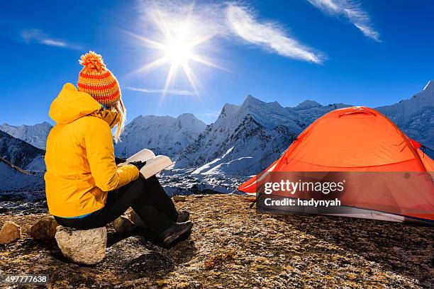 woman reading a book during sunrise over himalayas, everest region - himalayas sunrise stock pictures, royalty-free photos & images