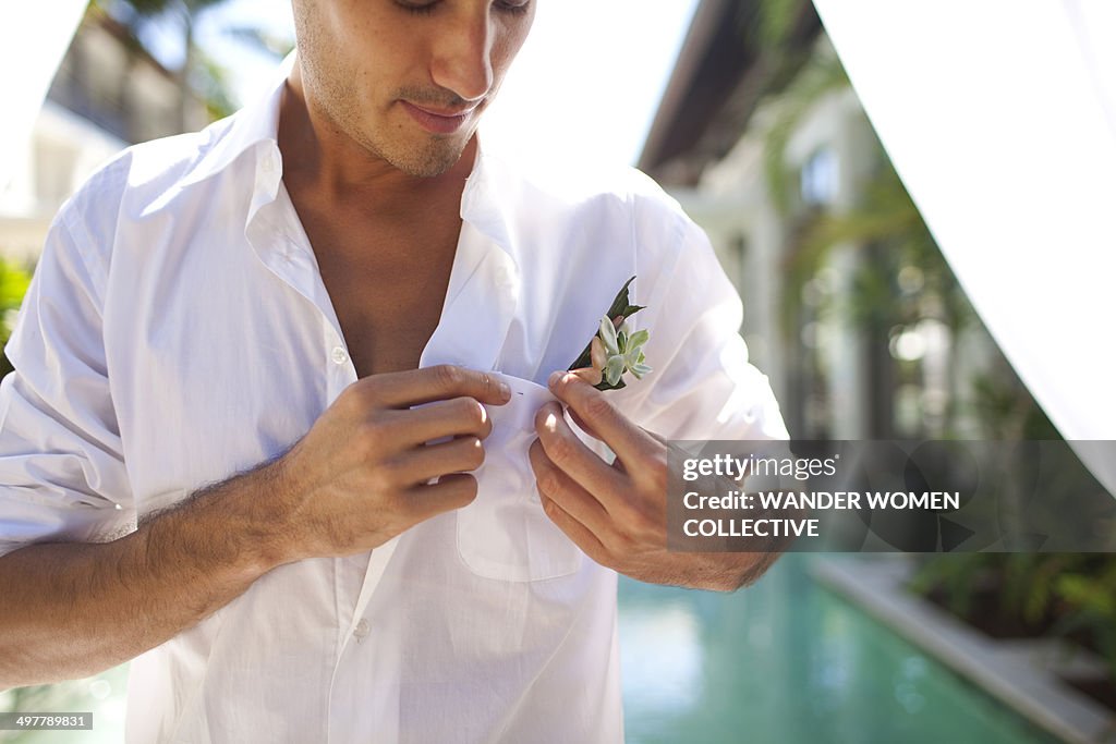 Groom pinning flowers to his shirt