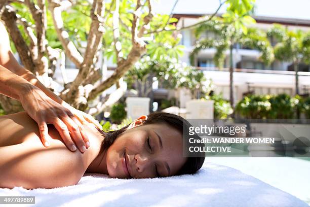 woman having massage by a resort pool - spa treatment stock pictures, royalty-free photos & images