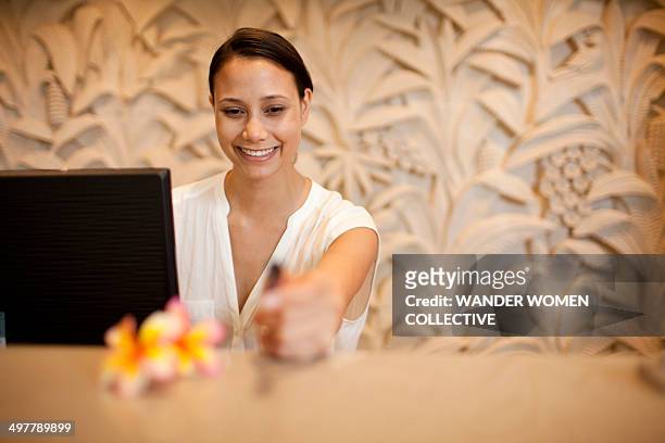 woman at hotel reception desk smiling - concierge foto e immagini stock
