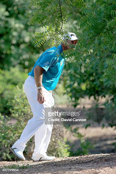 Lee Westwood of England peers through the trees lining up his second shot after a wild tee shot on the first hole during the first round of the 2015...
