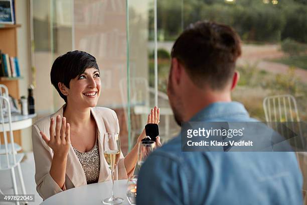 girlfriend looking happy after recieving ring - man proposing indoor stock-fotos und bilder