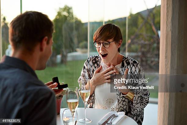 man giving engagement ring to girlfriend - man proposing indoor stock-fotos und bilder
