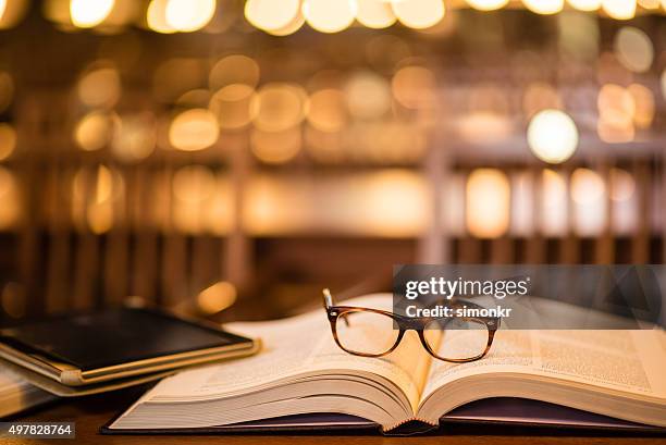 reading glasses and digital tablet on book - wise stock pictures, royalty-free photos & images