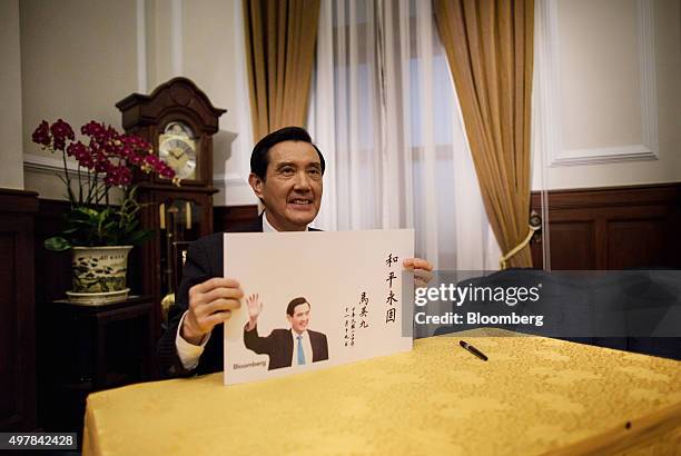 Ma Ying-jeou, Taiwan's president, poses for a photograph with a drawing he wrote using Chinese calligraphy prior to an interview at the presidential...