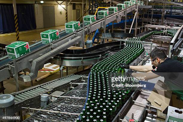 An employee lifts bottles of Heineken beer from the production line at the Heineken NV brewery in Saint Petersburg, Russia, on Wednesday, Nov. 18,...