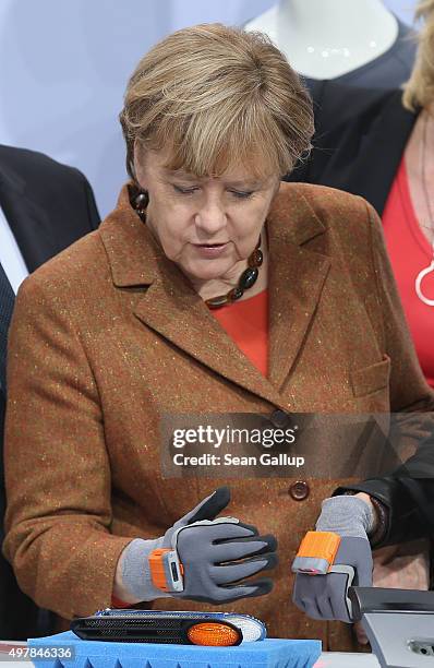 German Chancellor Angela Merkel attempts to try out a ProGlove smart glove for industrial use at the 2015 IT Summit on November 19, 2015 in Berlin,...