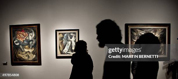 Workers of the Bellas Artes Museum passe by works of Mexican painter David Alfaro Siqueiros before the oppening of the exhibition "Exposicion...