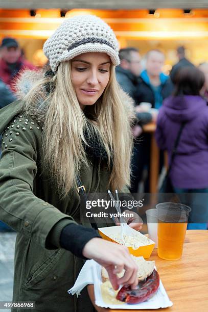 tasting sausage front of christmas kiosk - prague food stock pictures, royalty-free photos & images