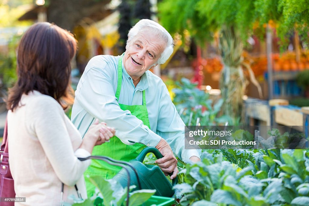 Senior dipendente deliziosi piante e giardinaggio negozio, aiutando il cliente