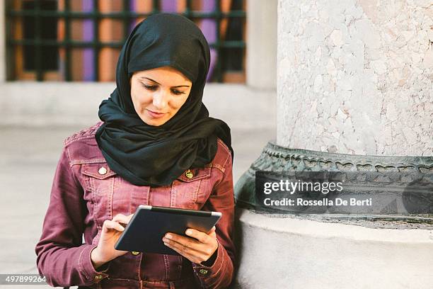retrato de una mujer joven usando tableta al aire libre con pañuelo de cabeza - arab businesswoman with books fotografías e imágenes de stock