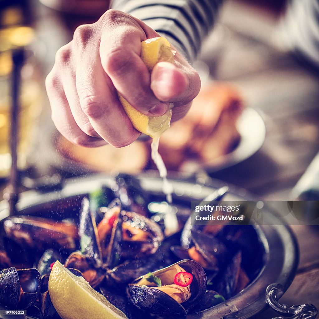 Squeezing Lemon on Classic French Mussels Dish