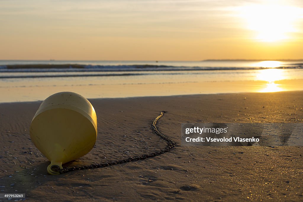 Yellow buoy at sunset during low tide