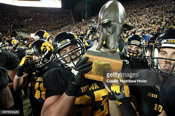 Offensive lineman Austin Blythe and kicker Marshall Koehn of the Iowa Hawkeyes carry The Floyd of Rosedale trophy off the field after defeating the...