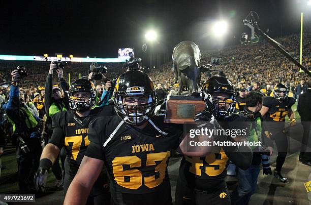 Offensive lineman Austin Blythe and defensive end Melvin Spears of the Iowa Hawkeyes carry The Floyd of Rosedale trophy off the field after defeating...