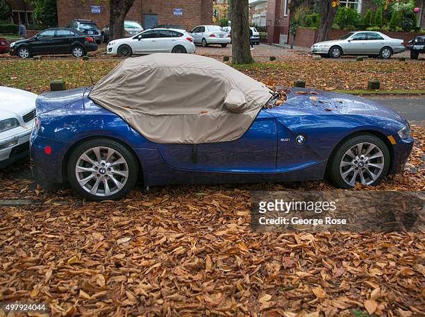 Golden leaves fall on a covered BMW automobile indicating that it is still autumn on November 5 in Seattle, Washington. Seattle, located in King...