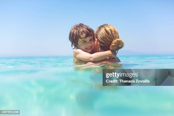 small boy hugging his mother in the sea - beautiful greek women stock pictures, royalty-free photos & images