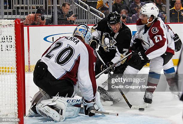 Evgeni Malkin of the Pittsburgh Penguins takes a shot in front of Reto Berra and Andreas Martinsen of the Colorado Avalanche at Consol Energy Center...