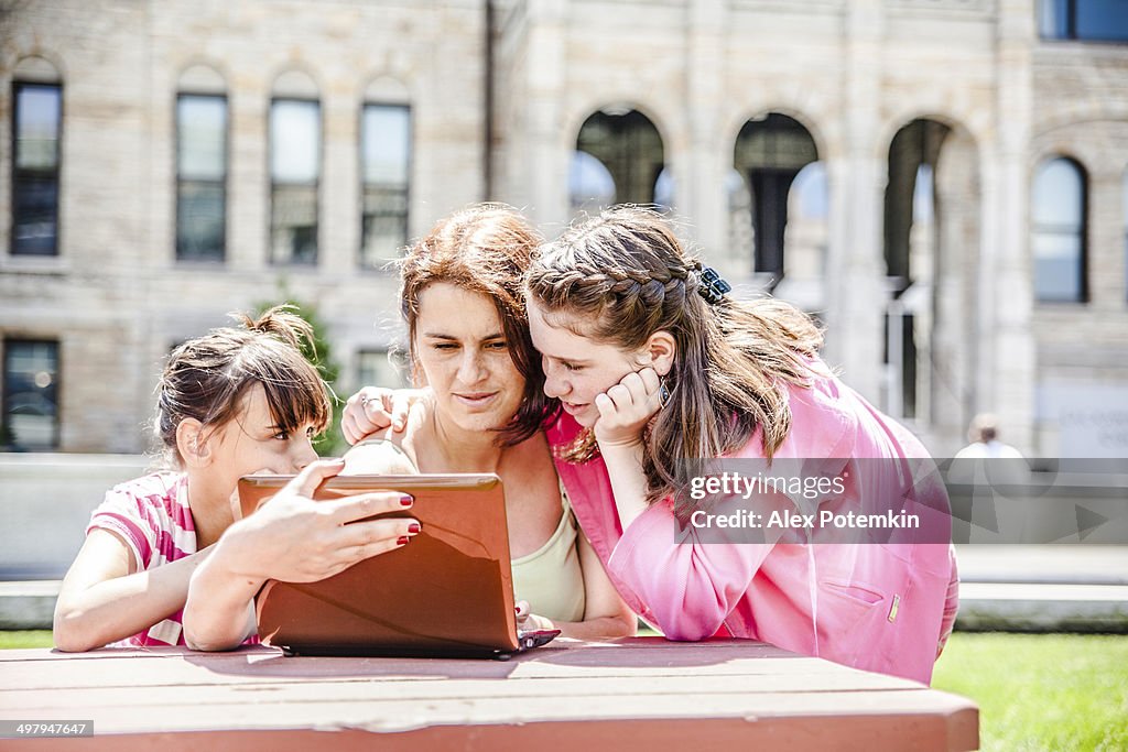 Family, mother with two daughters, reading info at the laptop