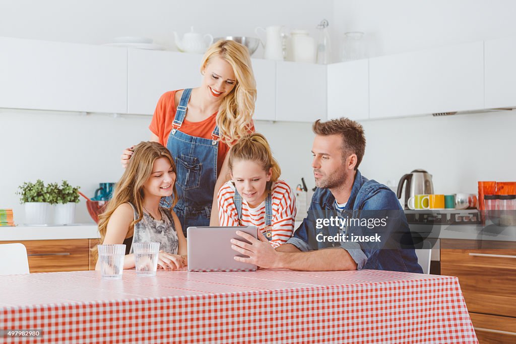 Famille heureuse à l'aide d'une tablette numérique dans la cuisine