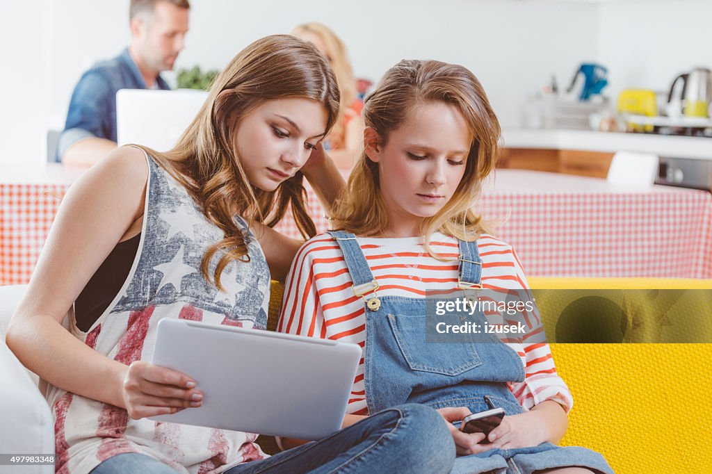 Teenage sisters using a digital tablet and smart phone