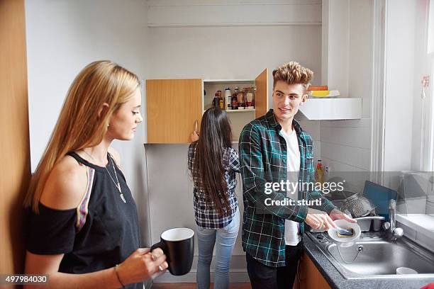 flatmates washing dishes in the kitchen. - dorm kitchen stock pictures, royalty-free photos & images
