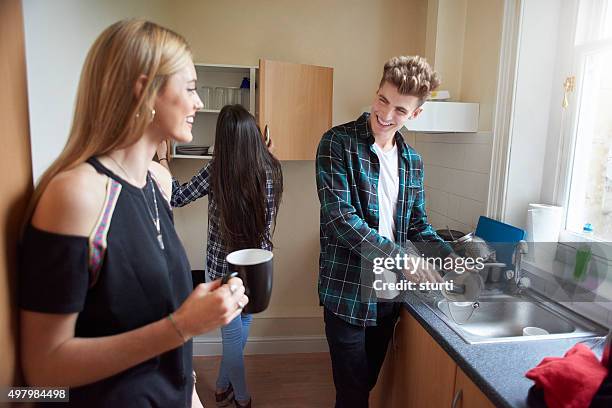 flatmates washing dishes in the kitchen. - dorm kitchen stock pictures, royalty-free photos & images