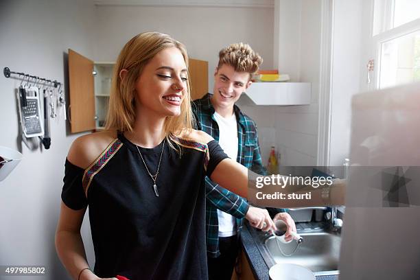 zwei flatmates waschen geschirr in der küche. - studentenwohnung stock-fotos und bilder