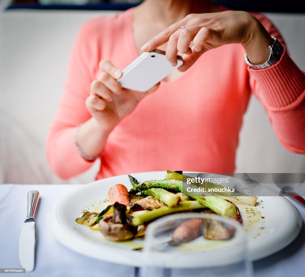 Woman photographing food with mobile phone