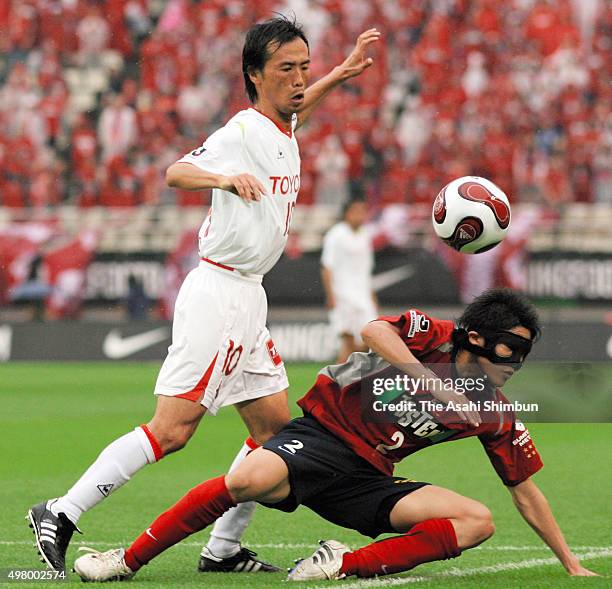 Toshiya Fujita of Nagoya Grampus Eight and Atsuto Uchida of Kashima Antlers compete for the ball during the J.League match between Kashima Antlers...